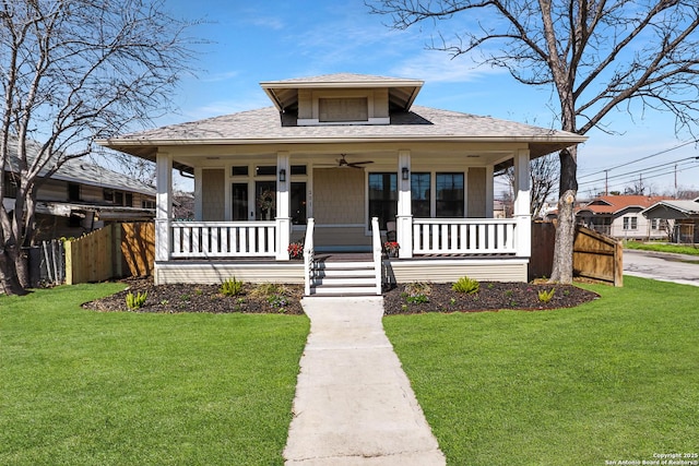 bungalow with covered porch, a front lawn, fence, and a ceiling fan