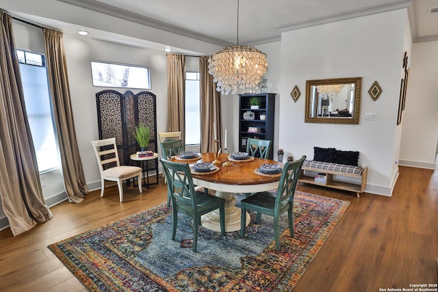 dining area featuring hardwood / wood-style flooring, baseboards, ornamental molding, and a notable chandelier