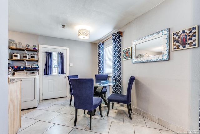 dining area featuring a wealth of natural light, washer / clothes dryer, light tile patterned flooring, and a textured ceiling