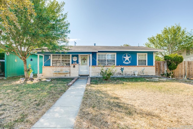 ranch-style house featuring brick siding, fence, and a front yard