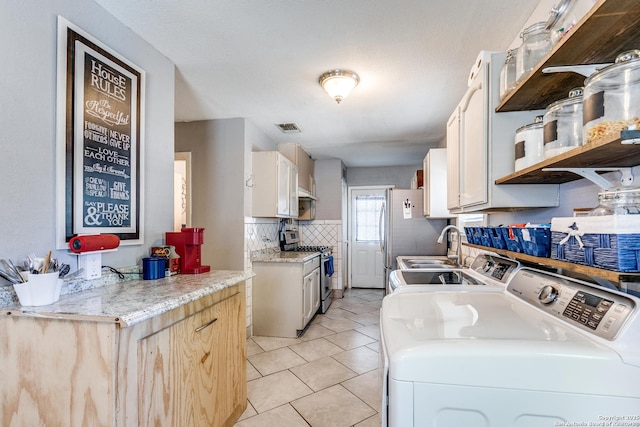 laundry room with laundry area, light tile patterned floors, visible vents, washer and clothes dryer, and a sink