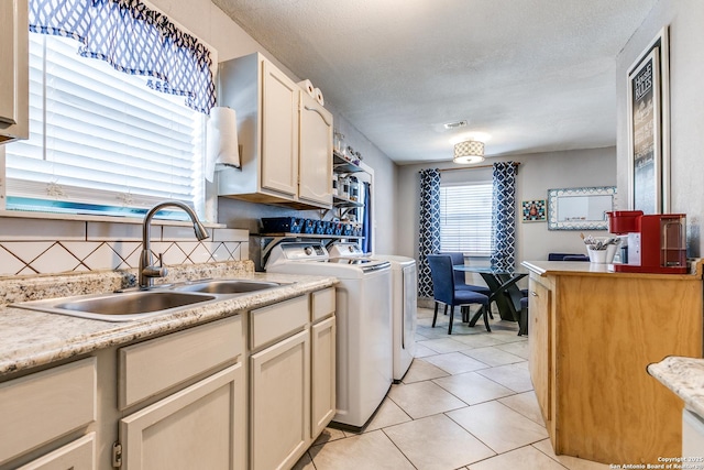 kitchen with light tile patterned floors, decorative backsplash, light countertops, separate washer and dryer, and a sink