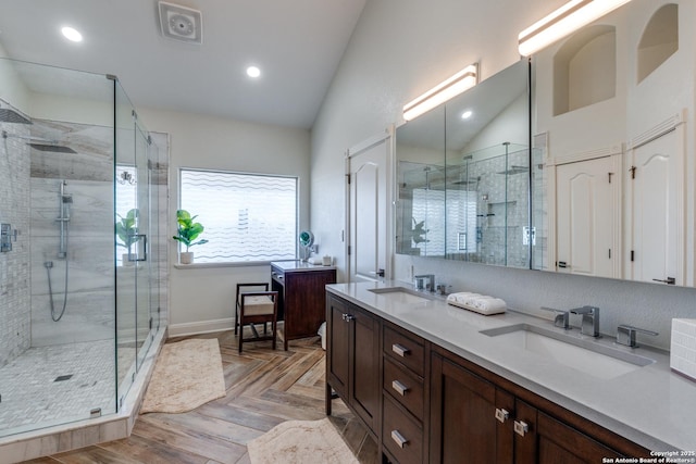 bathroom with vaulted ceiling, double vanity, a sink, and a shower stall