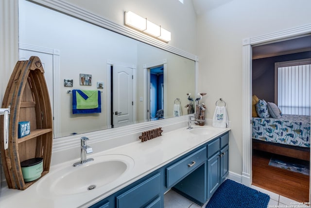 ensuite bathroom featuring double vanity, tile patterned floors, a sink, and connected bathroom