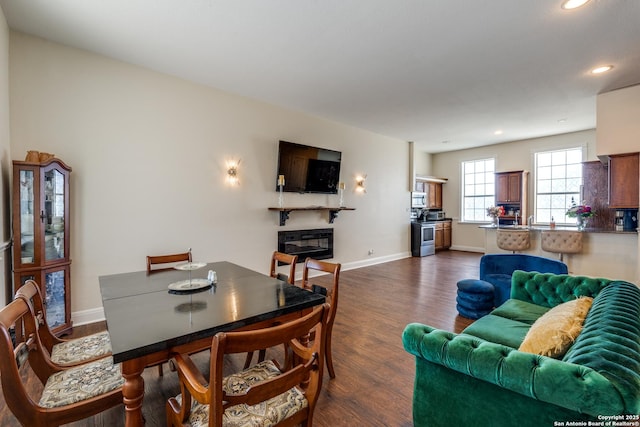 living area with dark wood-style floors, recessed lighting, baseboards, and a glass covered fireplace