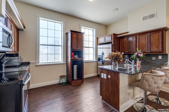 kitchen featuring dark wood-type flooring, visible vents, stainless steel appliances, and a sink
