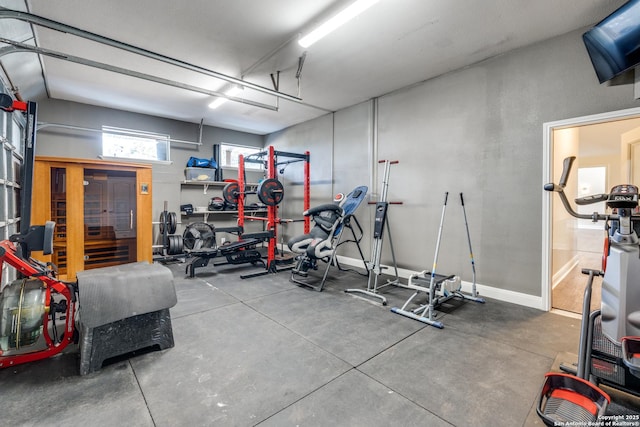 exercise room featuring a garage and baseboards