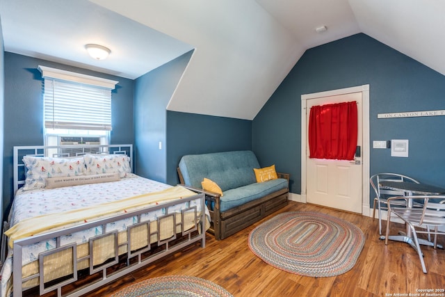 bedroom with lofted ceiling, baseboards, and wood finished floors