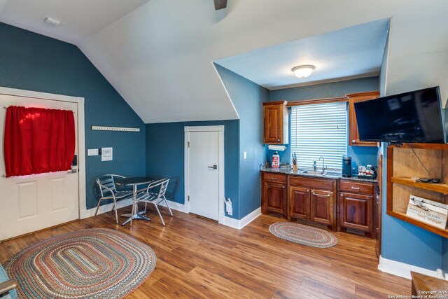 interior space featuring lofted ceiling, baseboards, and light wood-style floors