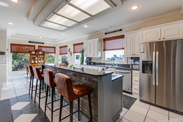 kitchen with a kitchen island, appliances with stainless steel finishes, a kitchen breakfast bar, and ornamental molding