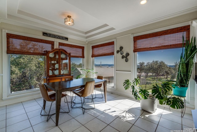 dining space with light tile patterned flooring, a tray ceiling, and ornamental molding