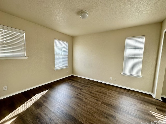 spare room featuring a textured ceiling, baseboards, and wood finished floors