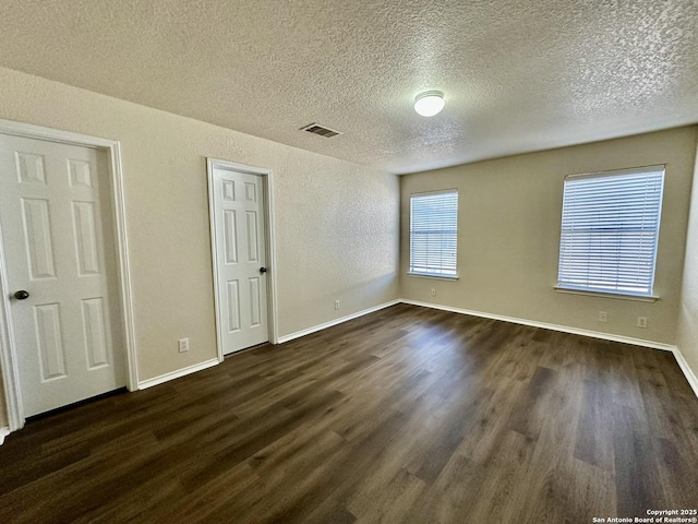 unfurnished bedroom featuring baseboards, a textured ceiling, visible vents, and dark wood-style flooring