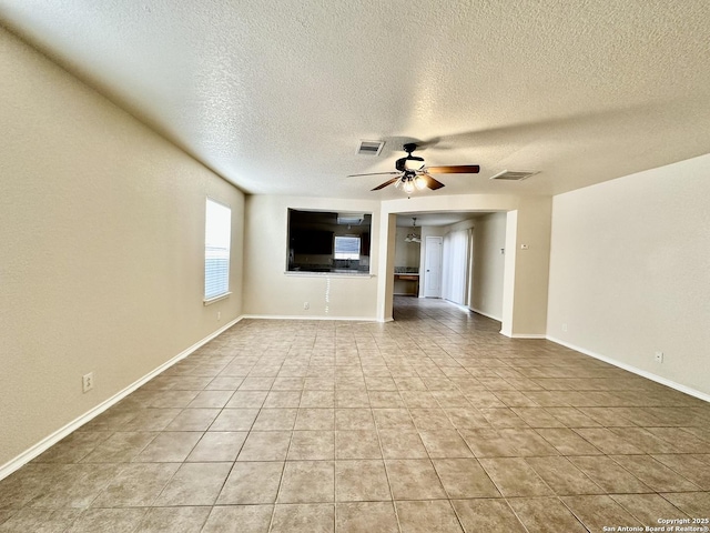 unfurnished living room featuring ceiling fan, light tile patterned flooring, visible vents, and baseboards