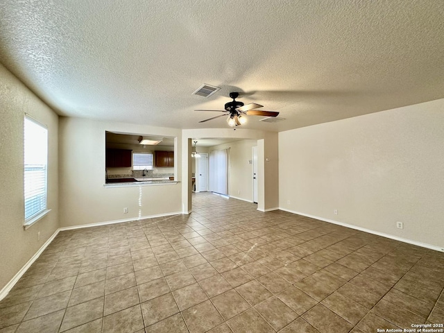 unfurnished living room featuring visible vents, ceiling fan, and baseboards