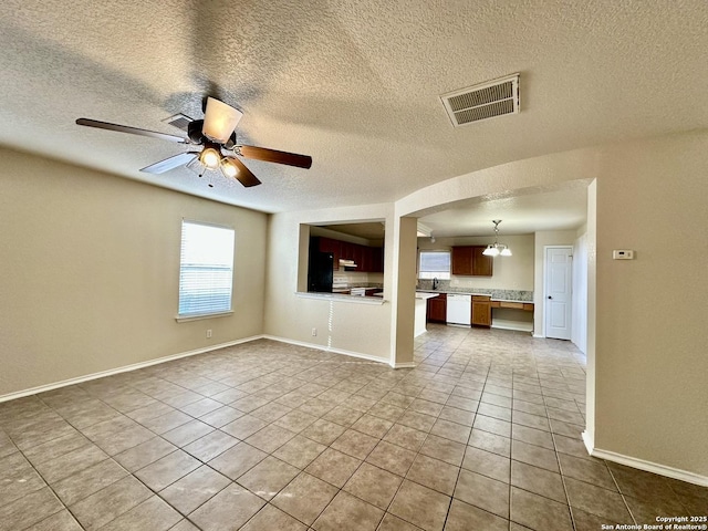 interior space featuring ceiling fan with notable chandelier, visible vents, a sink, baseboards, and tile patterned floors