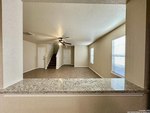 interior space featuring visible vents, stairway, a ceiling fan, a textured ceiling, and tile patterned flooring