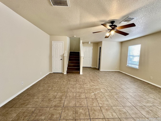 spare room featuring ceiling fan, stairway, tile patterned flooring, and visible vents