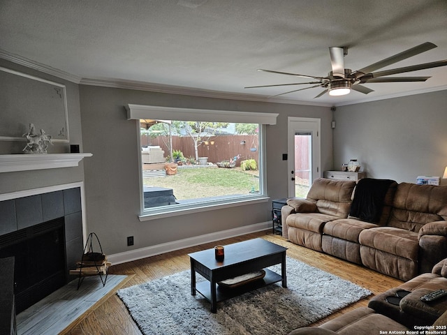 living area featuring a textured ceiling, a fireplace, wood finished floors, baseboards, and crown molding