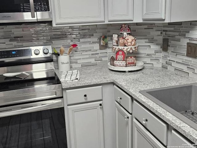 kitchen with white cabinets, appliances with stainless steel finishes, decorative backsplash, and a sink