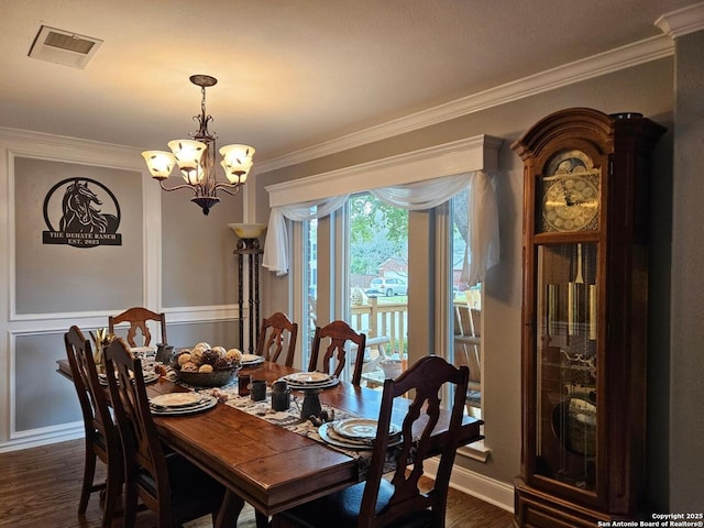 dining space with visible vents, wainscoting, dark wood-style flooring, an inviting chandelier, and crown molding