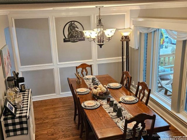 dining room with a chandelier, ornamental molding, wood finished floors, and a decorative wall