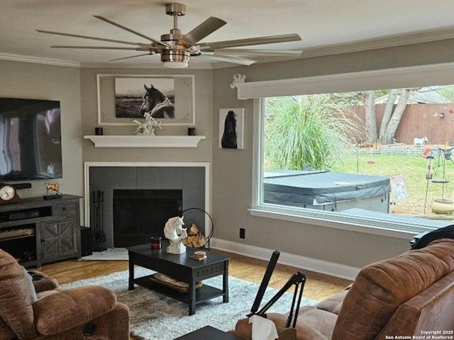 living room featuring crown molding, baseboards, wood finished floors, and a tile fireplace