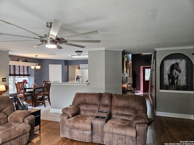 living area with crown molding, baseboards, wood finished floors, and ceiling fan with notable chandelier