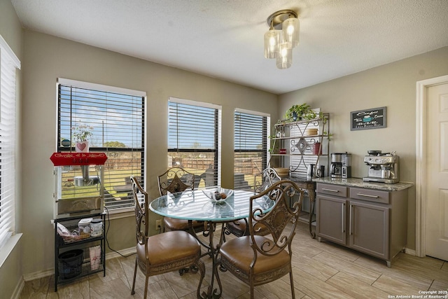 dining space with a textured ceiling, wood tiled floor, and baseboards