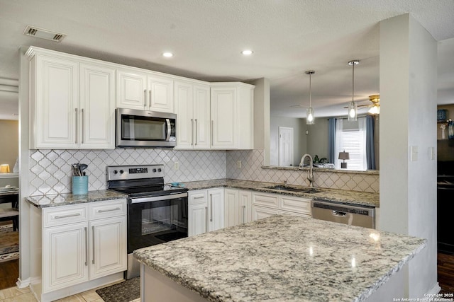 kitchen with stainless steel appliances, visible vents, white cabinetry, a sink, and light stone countertops