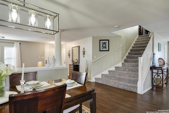 dining room featuring stairs, a textured ceiling, ornate columns, and wood finished floors