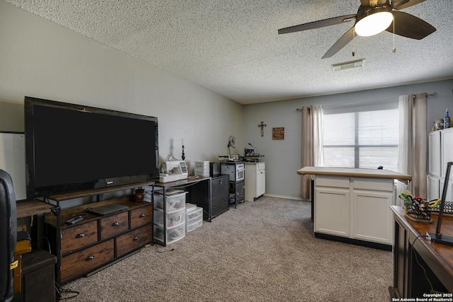 office with a textured ceiling, ceiling fan, visible vents, and light colored carpet