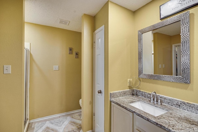 full bathroom with a stall shower, baseboards, visible vents, toilet, and vanity