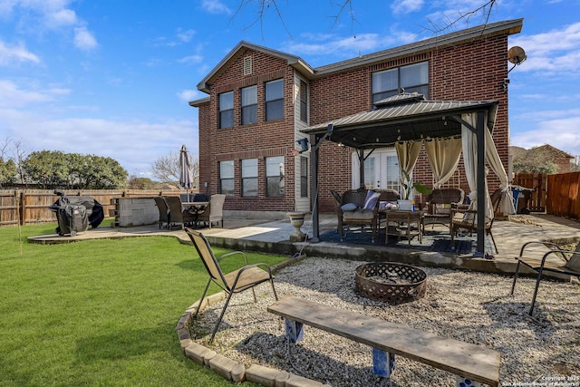 rear view of property with a fenced backyard, a gazebo, a yard, a patio area, and brick siding