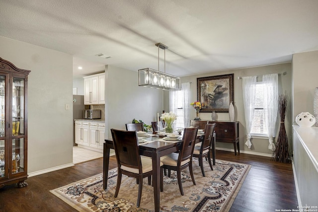 dining area featuring a notable chandelier, wood finished floors, visible vents, and baseboards