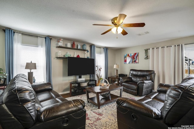 living room with ceiling fan, wood finished floors, visible vents, and a healthy amount of sunlight