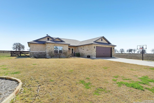 view of front of house with concrete driveway, an attached garage, a front yard, fence, and stone siding