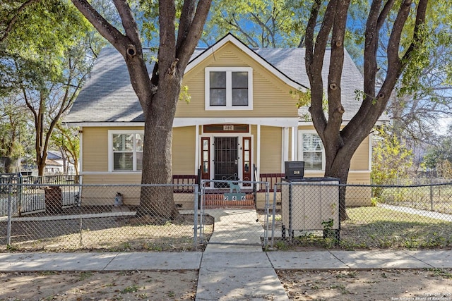 view of front of house featuring roof with shingles, a porch, a fenced front yard, and a gate