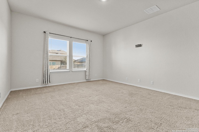 empty room with carpet floors, visible vents, and baseboards