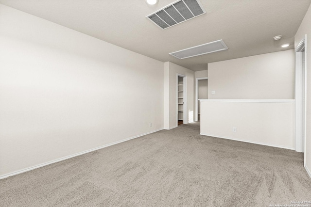 spare room featuring attic access, visible vents, baseboards, built in features, and carpet floors