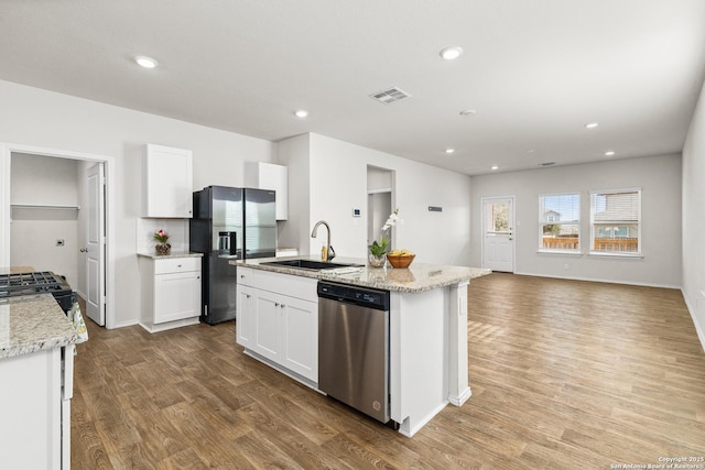 kitchen with stainless steel appliances, white cabinets, a sink, an island with sink, and wood finished floors