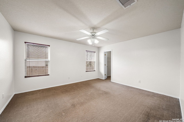 carpeted spare room featuring a textured ceiling, baseboards, visible vents, and a ceiling fan