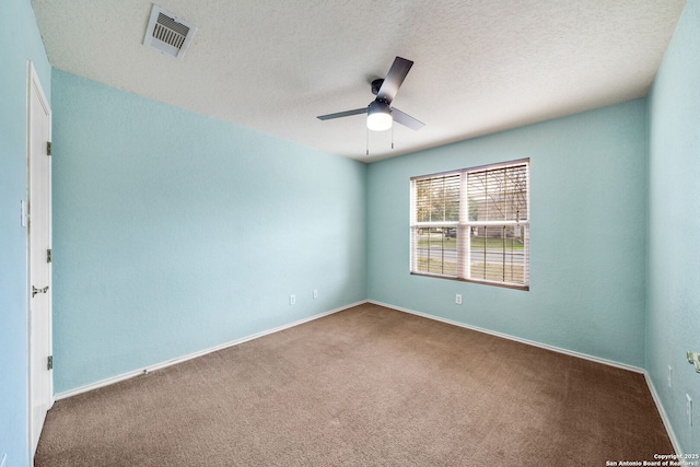 spare room with carpet, visible vents, ceiling fan, and a textured ceiling