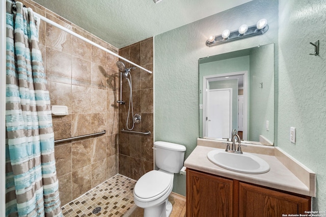 full bath featuring a textured ceiling, a textured wall, toilet, vanity, and tiled shower