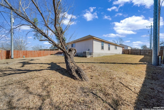 view of side of home with a fenced backyard, central AC unit, and a lawn