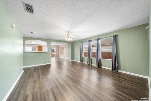 unfurnished living room with a ceiling fan, arched walkways, visible vents, and wood finished floors