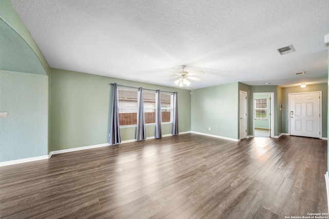 empty room with baseboards, visible vents, ceiling fan, wood finished floors, and a textured ceiling