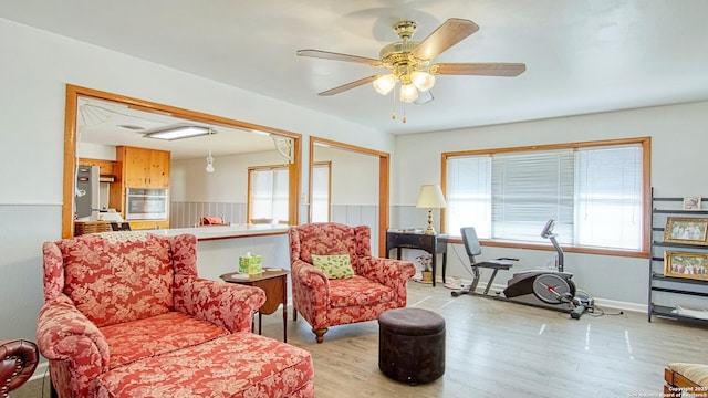 living area featuring wood finished floors, a ceiling fan, and baseboards