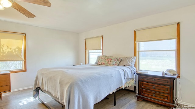 bedroom featuring ceiling fan, baseboards, and wood finished floors