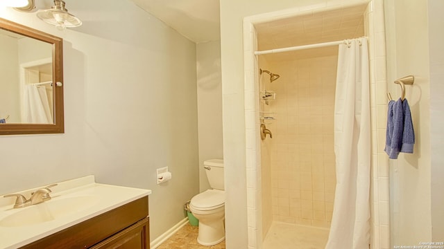 full bathroom featuring a stall shower, baseboards, vanity, and toilet